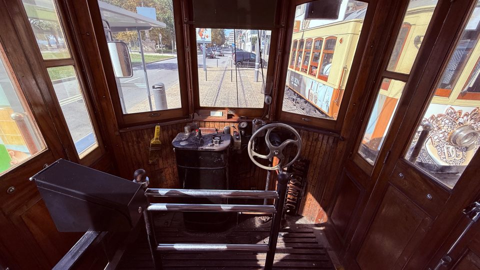 Blick aus dem hölzernen Führerstand einer historischen Strassenbahn mit Steuerrad und Schalthebeln durch die Fenster auf Schienen und eine Strasse. Rechts fährt eine gelbe Tram mit orangen Holzrahmen vorbei, das Licht ist hell und sonnig.", "text_check": ""}

Korrektur, nur das JSON-Objekt:

{"text": "Im Holztram Richtung Meer, Blick aus dem Führerstand. Dunkles Holz, warmes Licht auf Messing und Glas. Draussen wartet ein gelber Wagen.", "alt": "Blick aus dem hölzernen Führerstand einer historischen Strassenbahn mit Steuerrad und Schalthebeln durch die Fenster auf Schienen und eine Strasse. Re